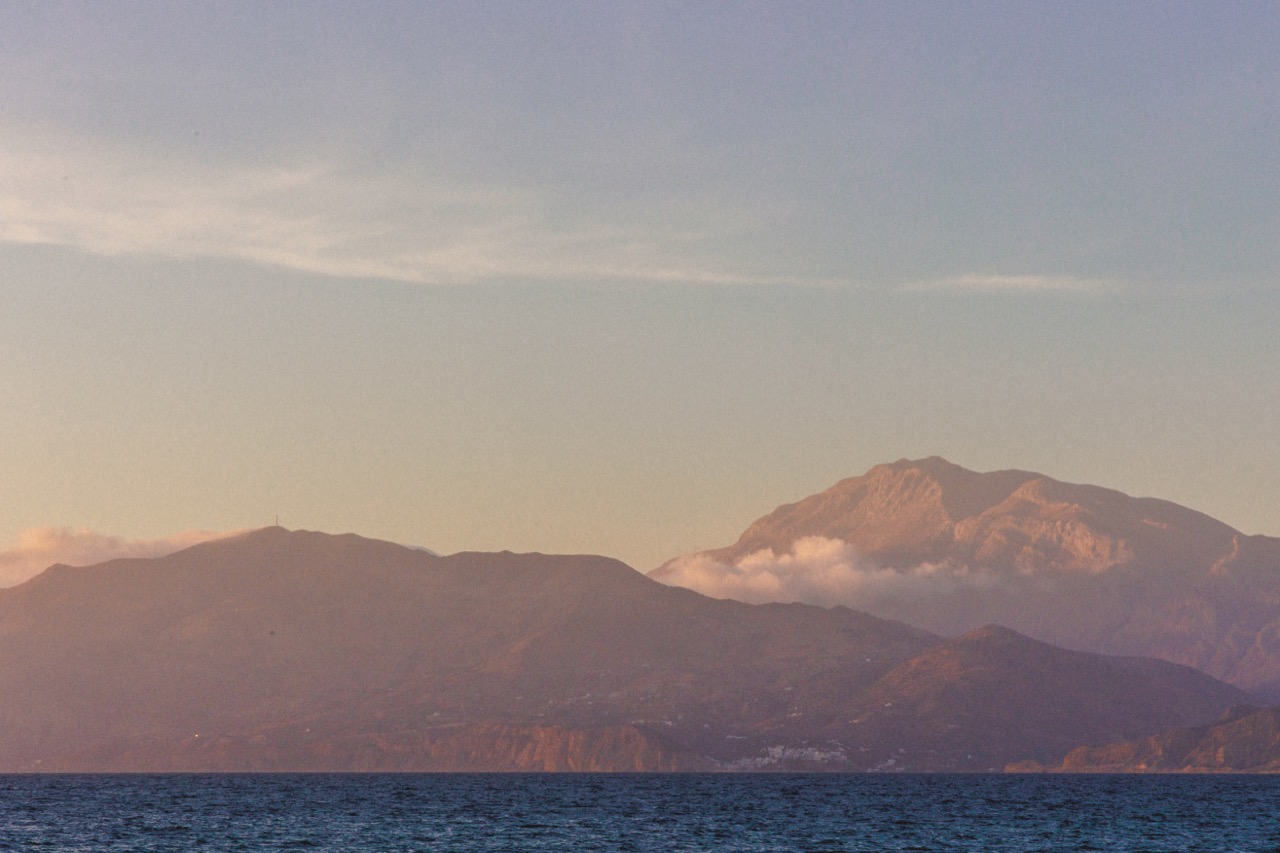 Mountains across the sea at dusk, cloud on the highest peak